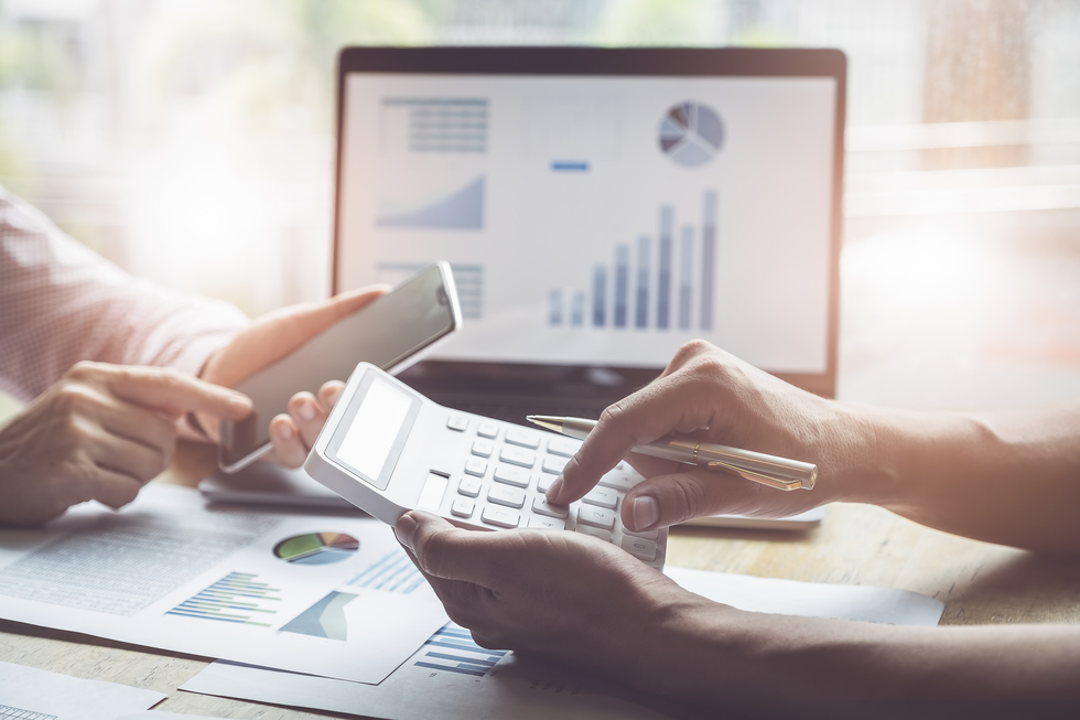 Business and partnership  discussing using calculator to review balance sheet annual with holding pen and using laptop computer to calculating budget. audit integrity before investment concept.